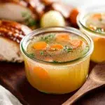 Homemade turkey stock simmering with herbs and vegetables in a pot.