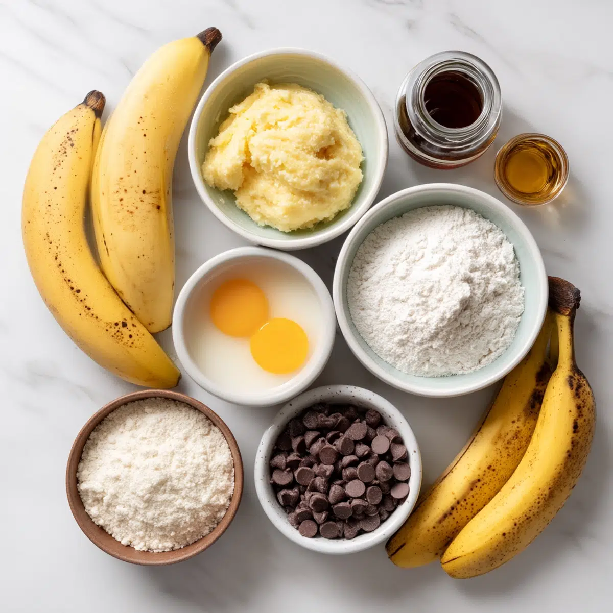 ingredients for banana chocolate chip muffins arranged in prep bowls overhead view