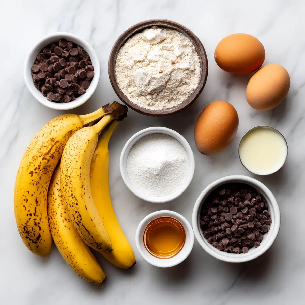 gluten free banana chocolate chip bread ingredients flat lay with ripe bananas, gluten-free flour, dark chocolate chips, coconut oil, and maple syrup