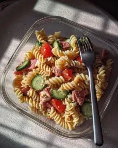 A vibrant protein-packed Italian pasta salad with colorful vegetables and dressing.