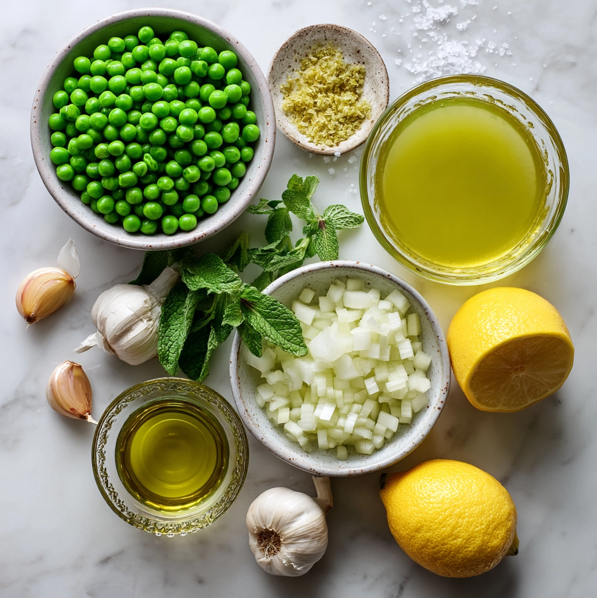 Spring pea soup recipe ingredients arranged on a cutting board including frozen peas, fresh mint, lemon, onion, garlic, and vegetable broth