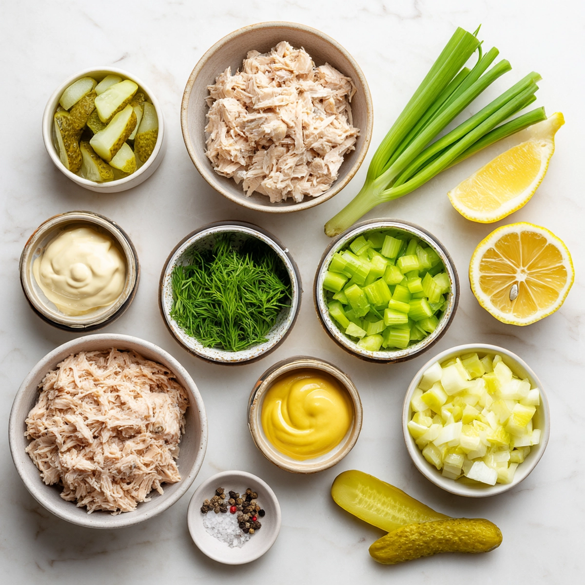 tuna salad recipe ingredients flat-lay including canned tuna, mayonnaise, celery, dill pickles, green onion, Dijon mustard, and lemon