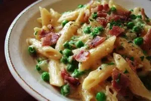 Delicious creamy bacon and pea pasta served in a bowl, garnished with herbs.