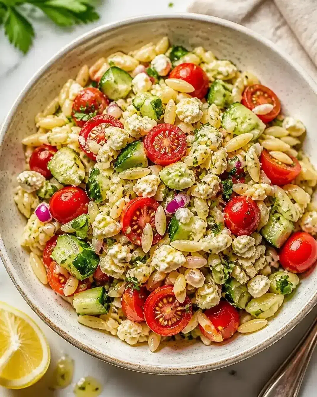 A colorful orzo salad with vegetables and herbs in a bowl